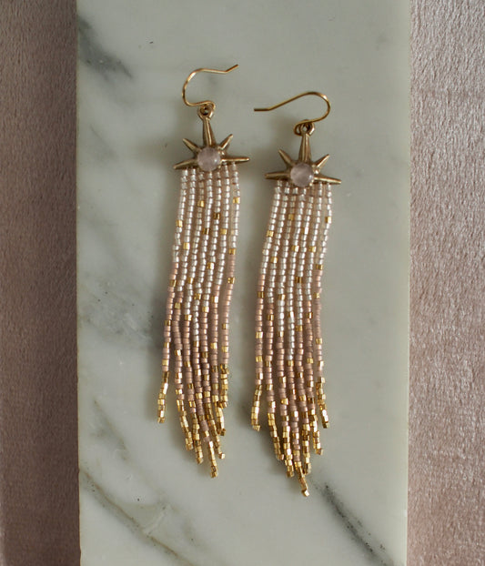 Star earrings with rose quartz, long beaded fringe, and gold accents on a marble surface