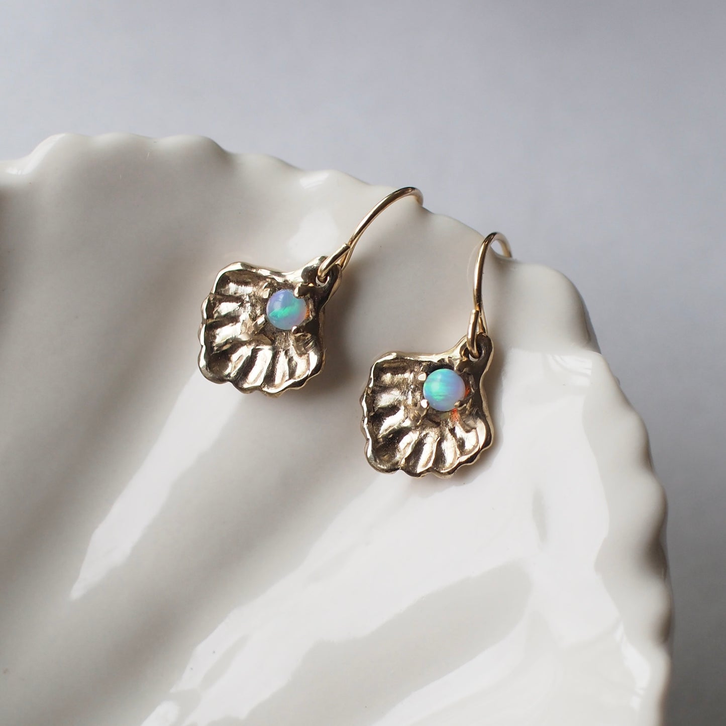 Oyster shell earrings containing a small opal "pearl", cast in gold tone bronze by Iron Oxide Designs