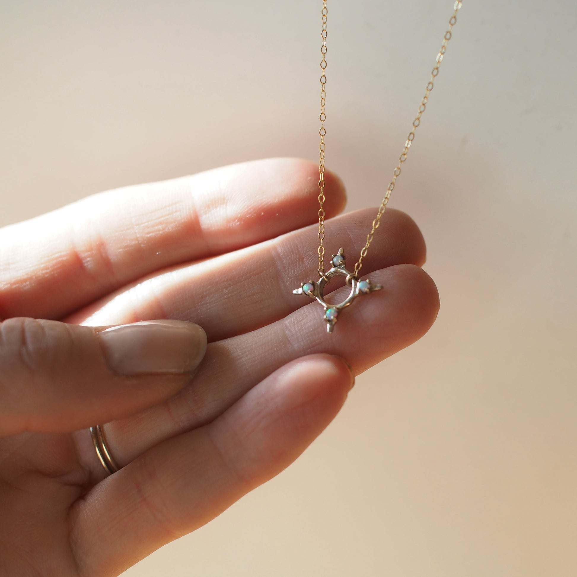 Four point star shaped Opal Eclipse Necklace by Iron Oxide designs made with 2mm lab grown opals set in bronze.
