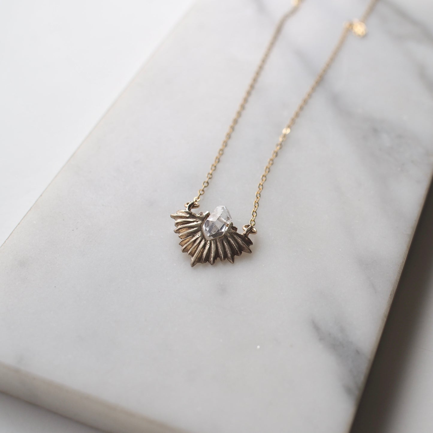 Bronze celestial and clear quartz crystal necklace on a gold chain by Iron Oxide Designs