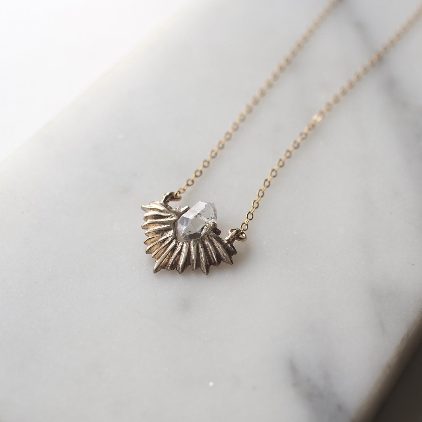 Bronze celestial and clear quartz crystal necklace on a gold chain by Iron Oxide Designs