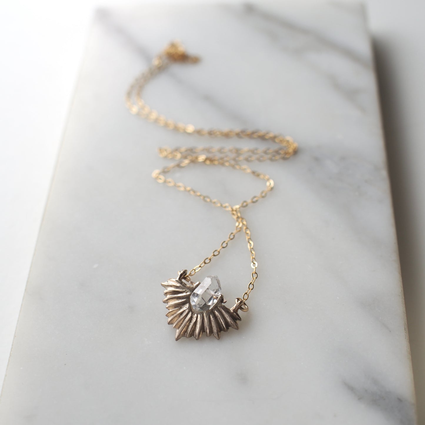 Bronze celestial and clear quartz crystal necklace on a gold chain by Iron Oxide Designs
