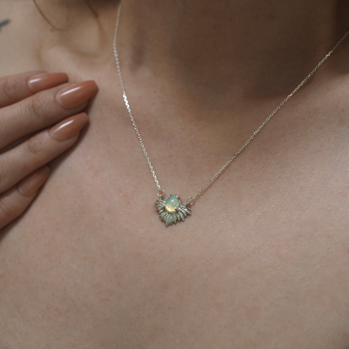 Cosmic opal necklace set in a sterling silver setting shown on a model for scale, handmade in the USA by Iron Oxide using sustainably sourced gemstones.