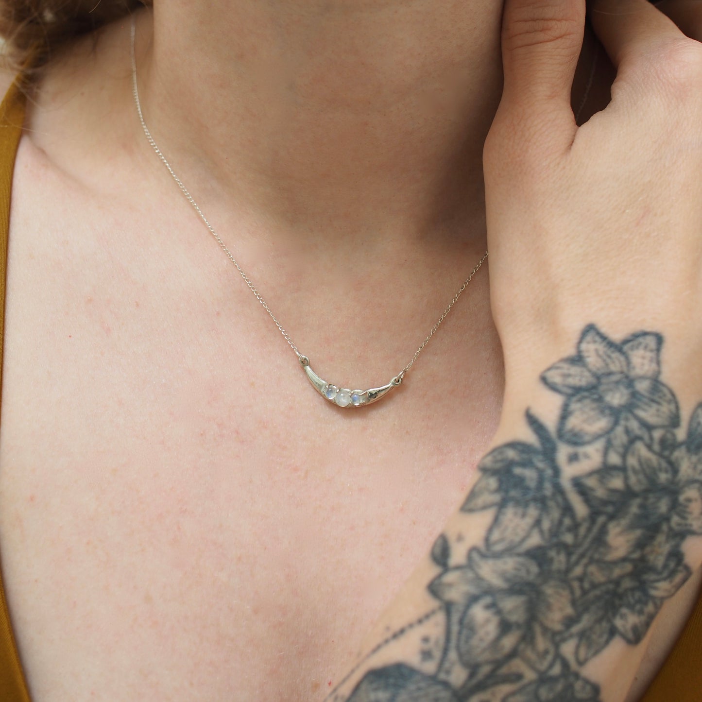Crescent Moon necklace set with sustainably sourced moonstone, set in sterling silver shown on a model for scale. Made by hand in the USA by Iron Oxide