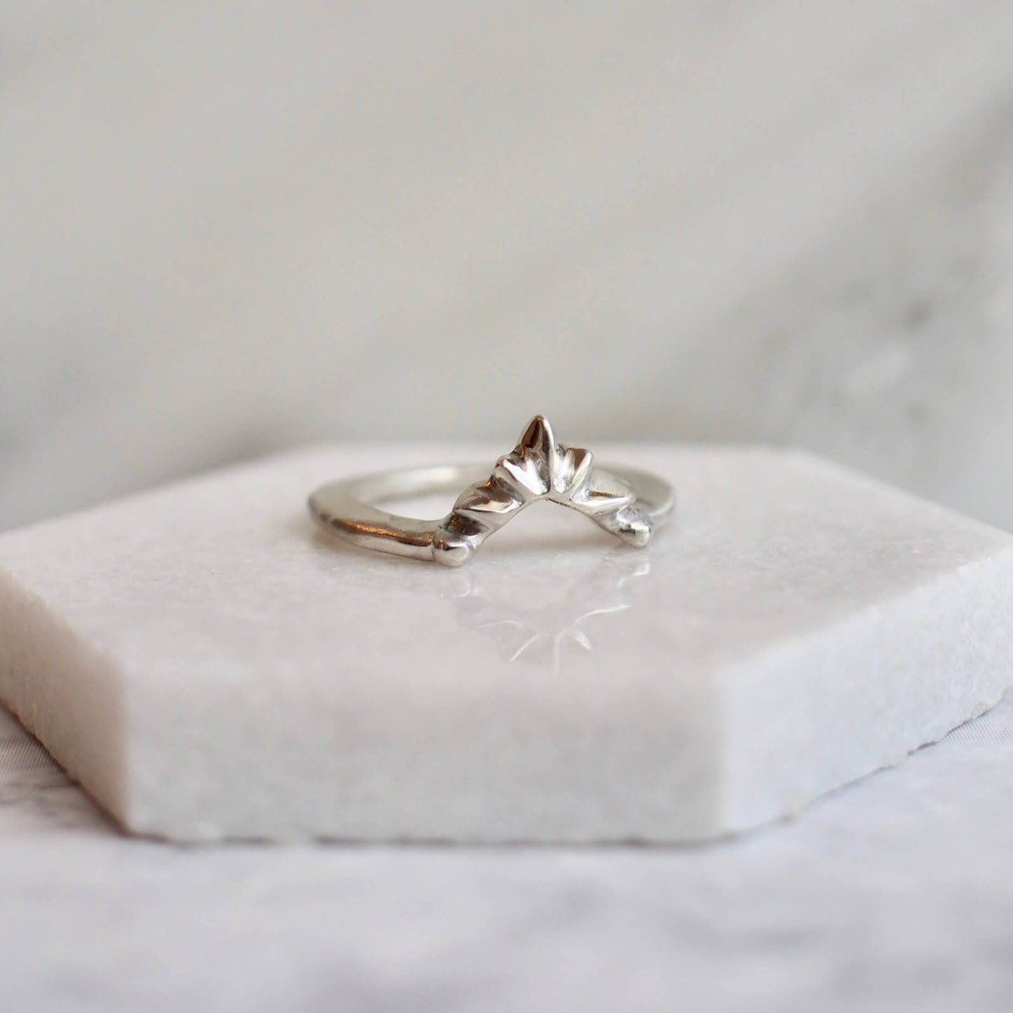 Sunburst shaped stacking band shown in sterling silver on a marble plate, handmade by Iron Oxide Designs