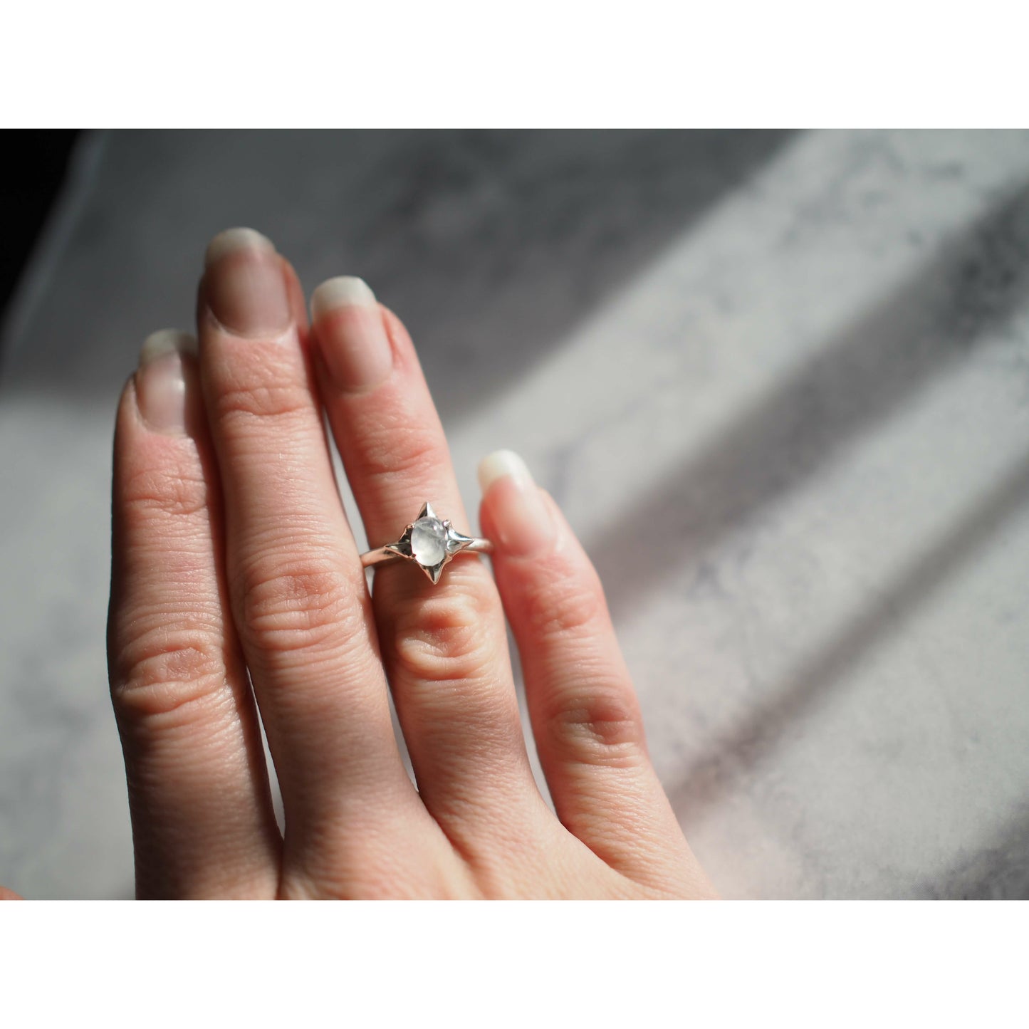 Ethically sourced moonstone star ring set in sterling silver from Iron Oxide Designs. Shown on a model for scale
