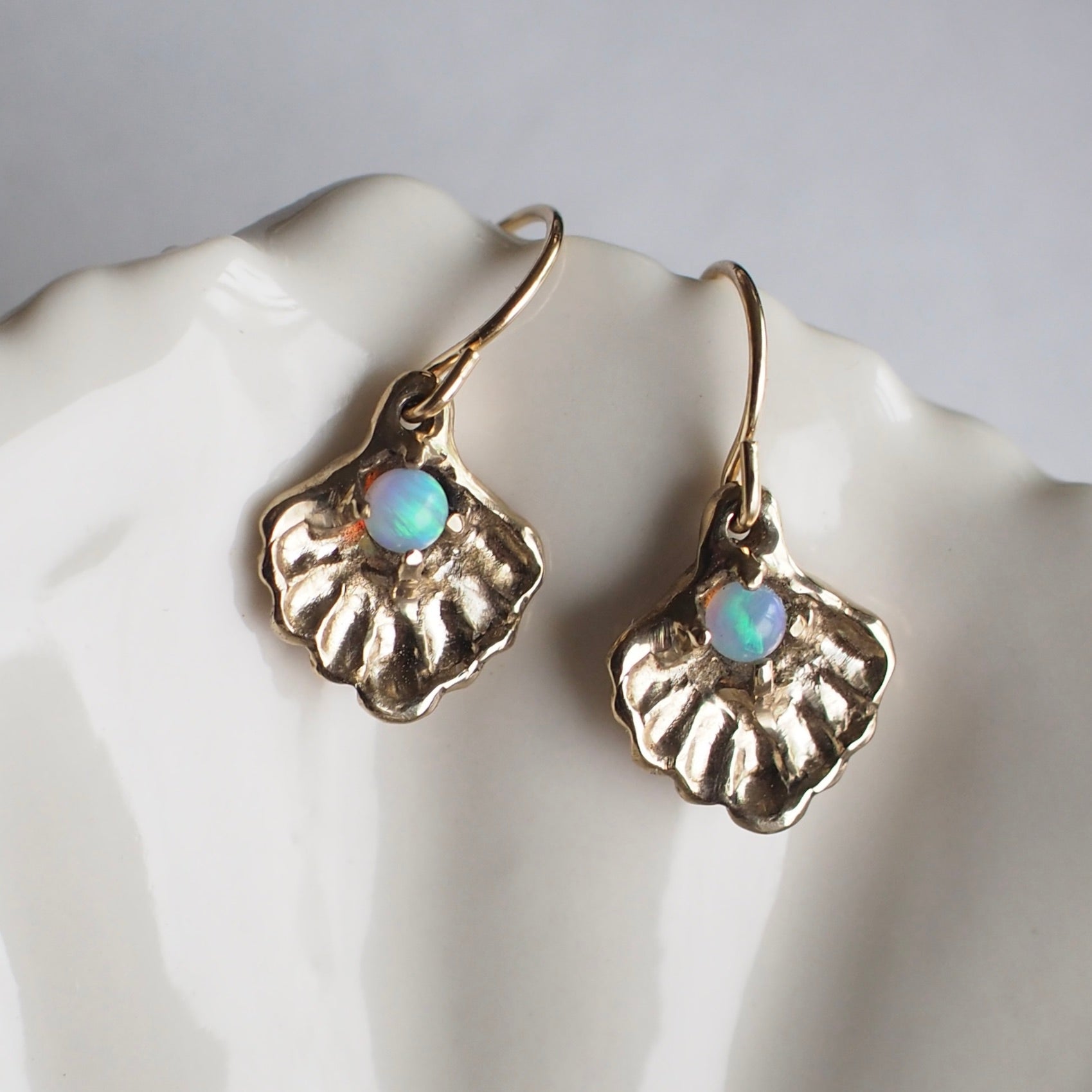 Oyster shell earrings containing a small opal "pearl", cast in gold tone bronze by Iron Oxide Designs