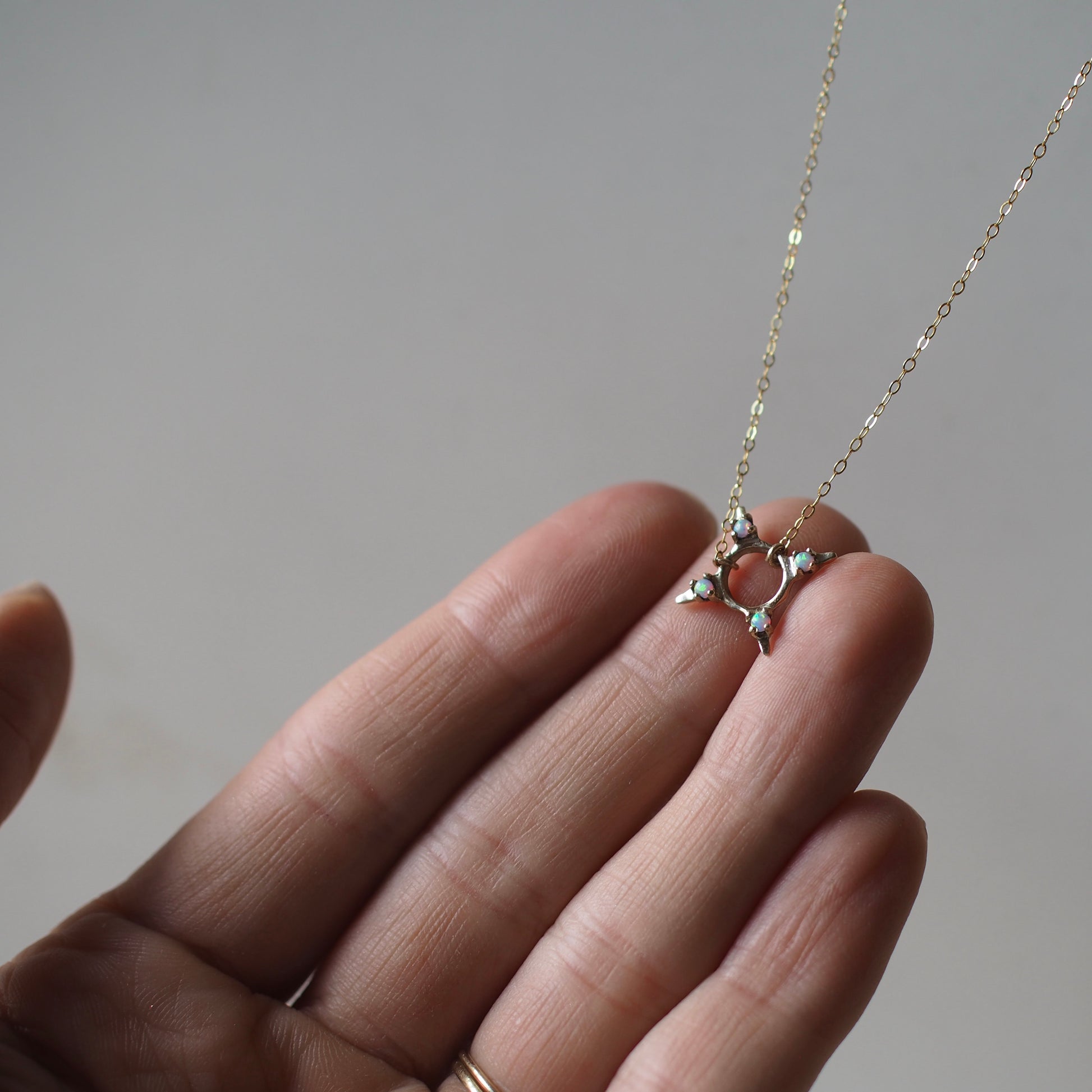 Four point star shaped Opal Eclipse Necklace by Iron Oxide designs made with 2mm lab grown opals set in bronze. 