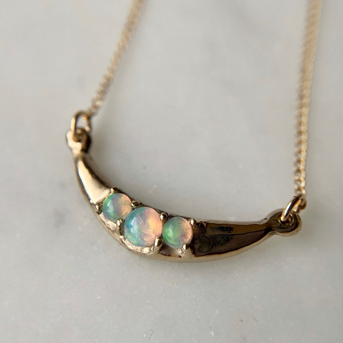Close up of crescent Moon necklace set with sustainably sourced opals cast in gold tone bronze by Iron Oxide