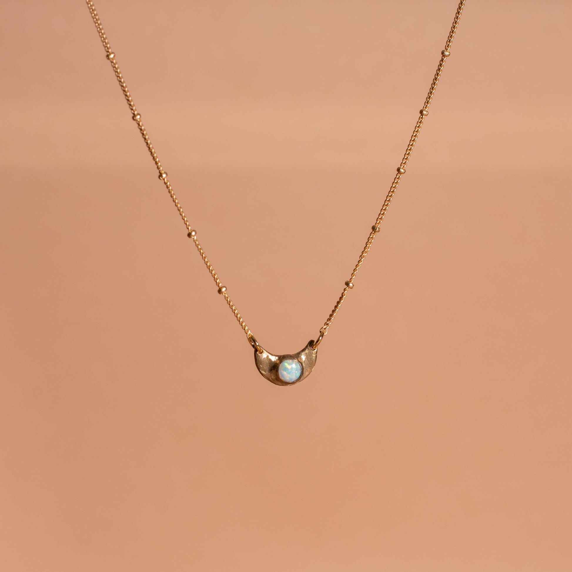 shiny gold toned Iron Oxide dainty moon necklace set with an opal gemstone