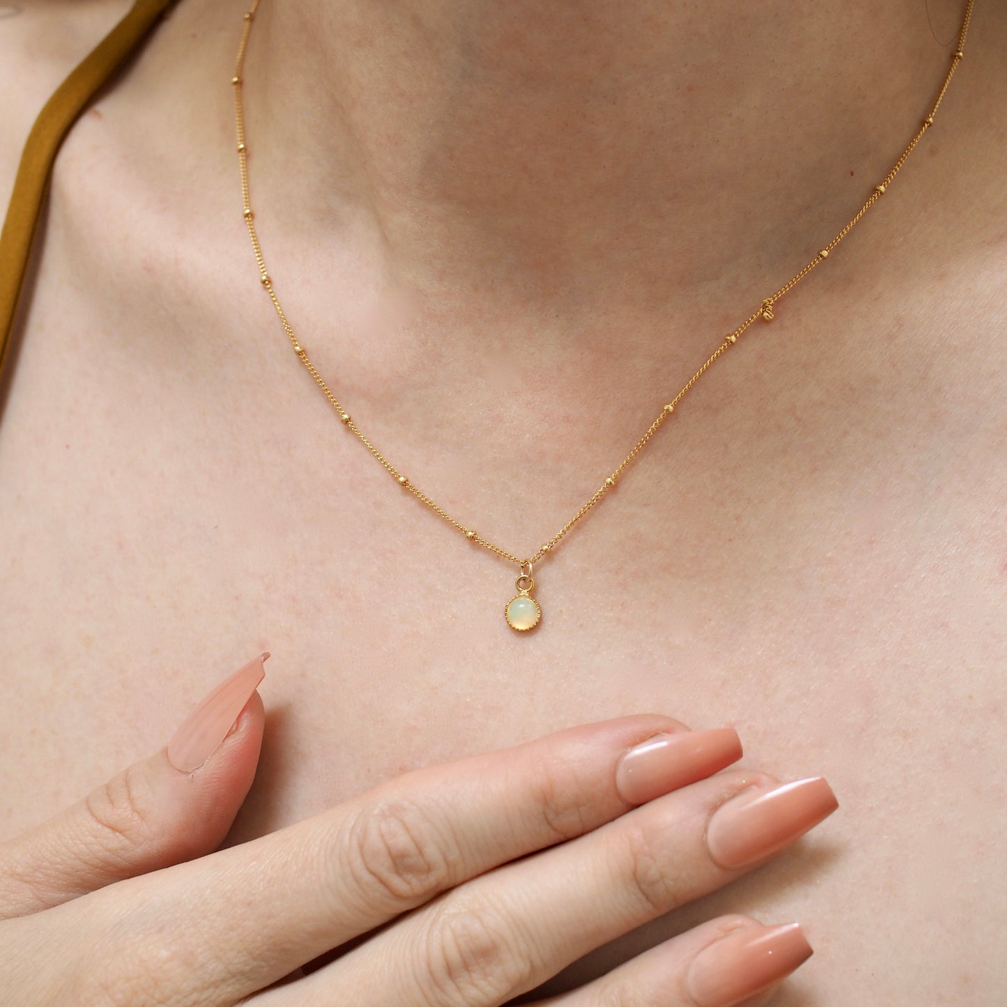 Dainty opal choker on a dotted gold fill chain shown on a model for scale.