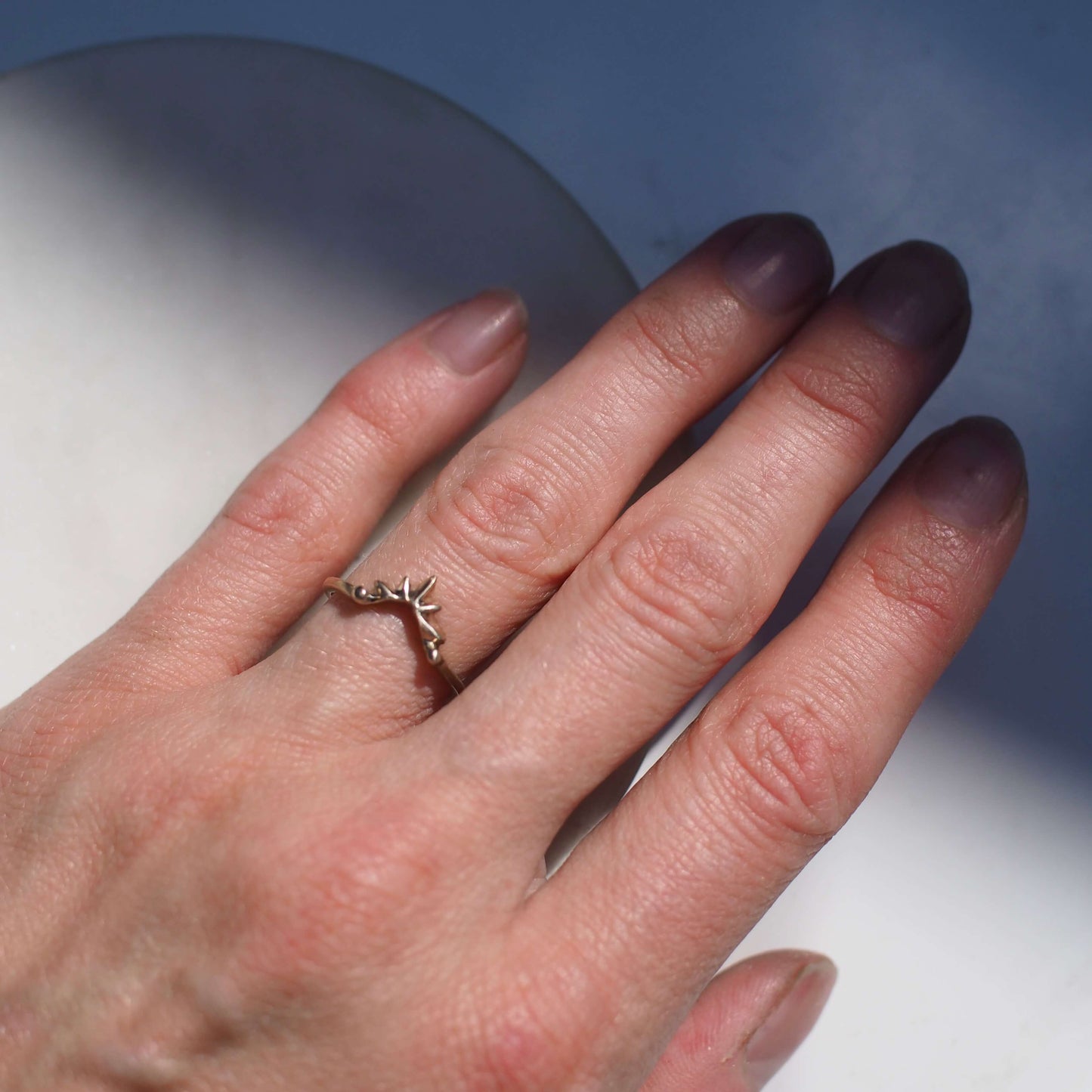 Sunburst shaped stacking band shown in gold tone bronze on a model's hand for scale, Handmade by Iron Oxide Designs