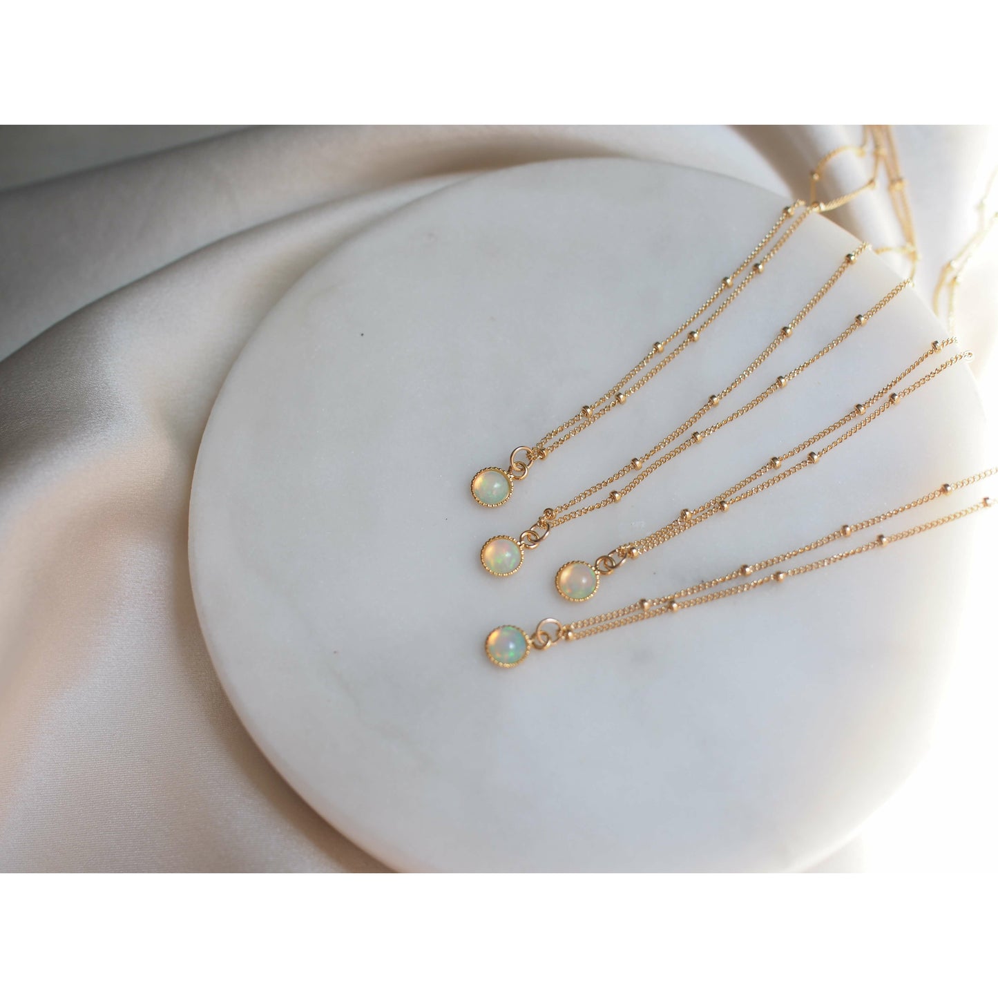Dainty opal chokers on a dotted gold fill chain shown on a marble backdrop