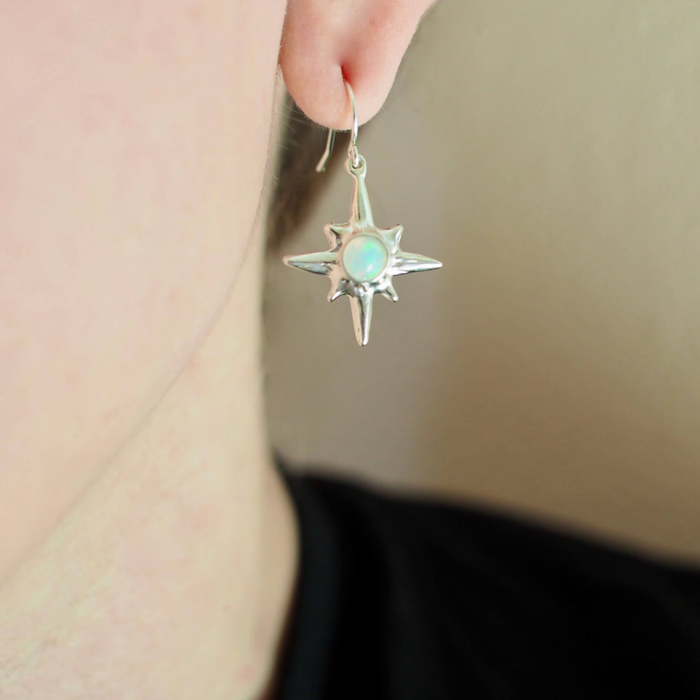 North Star earrings set with sustainably sourced opal artisan made jewelry by Iron Oxide Designs, shown on a model for scale