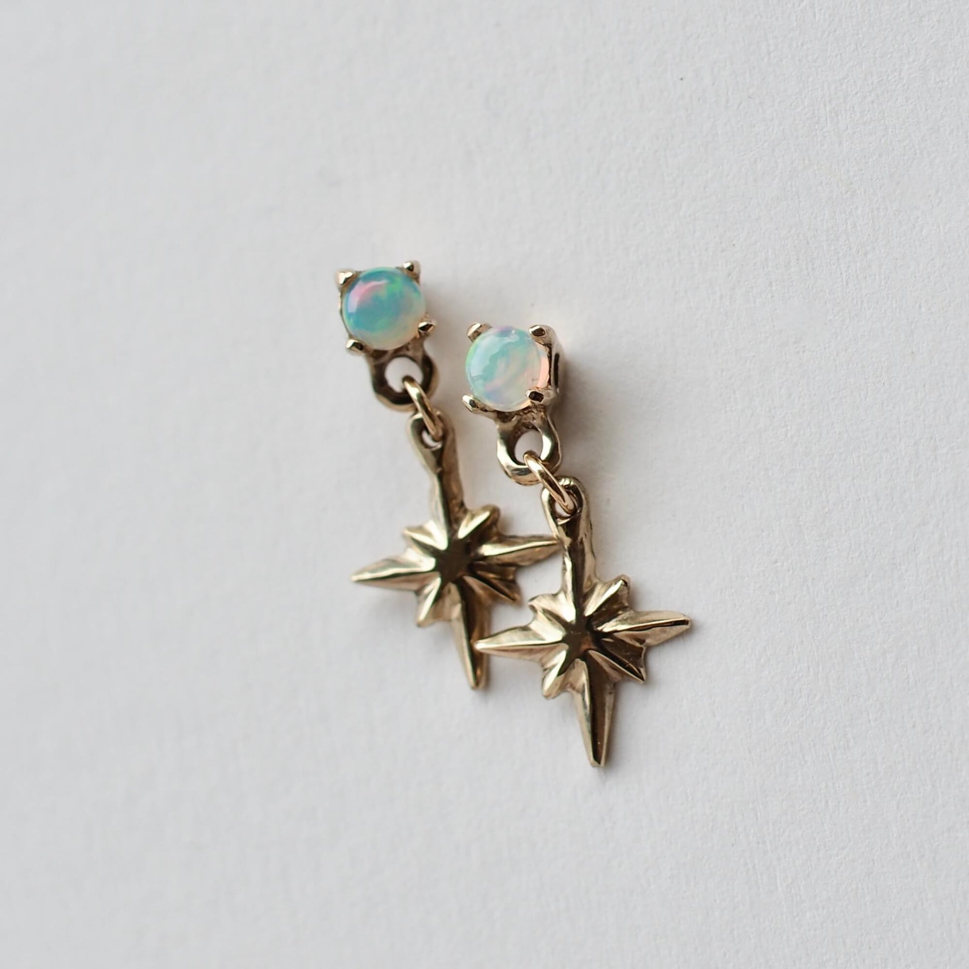Tiny star dangle earrings in gold tone bronze, set with opals