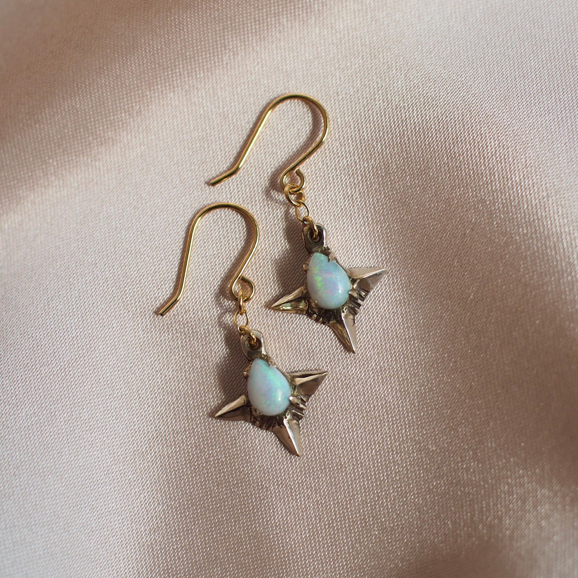 Teardrop shaped lab grown opal set in 4 point star setting in gold tone bronze handmade by Iron Oxide Designs