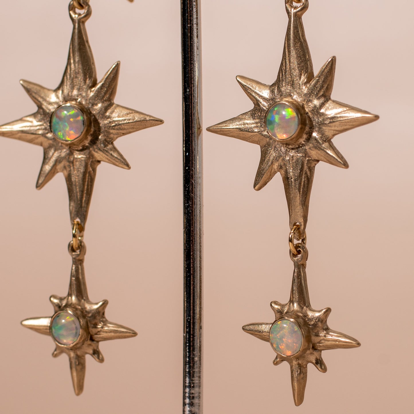 Close up of Iron Oxide Celestial Polaris Earrings set with lab grown fire opal